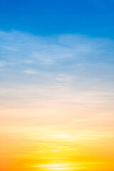 Sunset or sunrise sky with a vibrant gradient of orange, gold, and soft blue. Clear atmosphere with wispy clouds. Peaceful, natural light background. hope, freedom, new day Concepts, Vertical