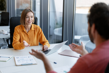 Happy woman, businesswoman talking with bearded man, provide feedback sitting in modern office