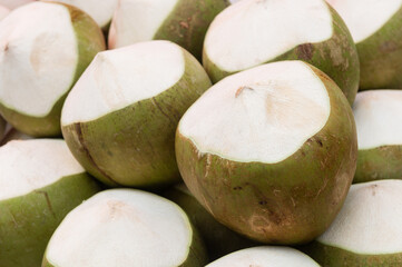 Fresh young coconuts displayed in a market with their tops neatly cut