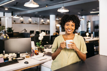 Smiling businesswoman holding coffee mug during office break
