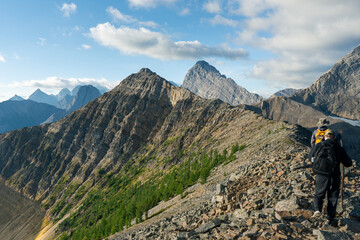 Obraz premium Hikers traverse a rocky mountain ridge, surrounded by stunning mountain views.