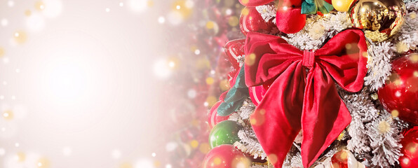 Red Christmas bow hanging on the Christmas tree. Magic details, balls, bokeh lights on background. Christmas, New Year, winter holiday. Copy space, empty place for message.