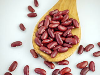 Red bean seeds on a wooden spoon on a white background
