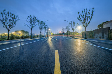 Empty asphalt road with a yellow marking line stretching into the distance at night.