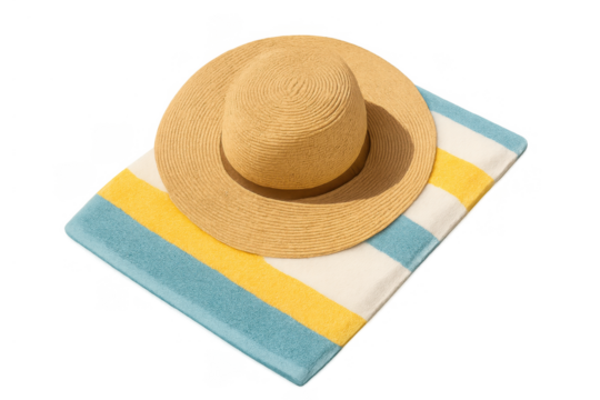 Straw hat resting on a striped beach towel, symbolizing summer vacation, travel, and relaxing by the ocean