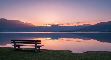 Serene sunrise over mountain lake with empty wooden bench and reflective water