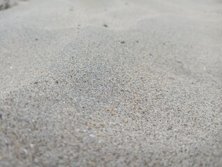 Close up of textured sand surface with subtle variations in grain and color creating a natural, abstract background for your projects.