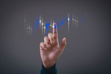 Hand pointing at digital candlestick chart showing stock or cryptocurrency trading analysis with...