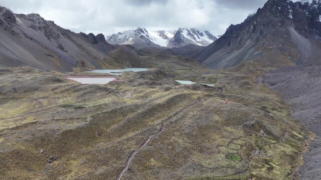 Aerial rises from China Otorongo Lake and moves toward Puca Cocha (Red Lagoon) and Pata Cocha Lake, with snow-capped Andes mountains visible in the background
