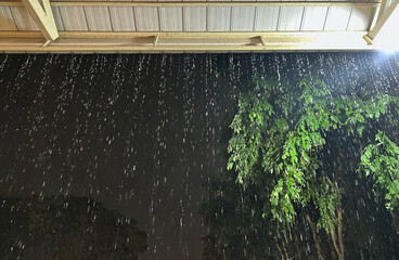 Rain Bomb Intensity: Flash Flooding Rainwater Cascading from Single-Story Home Roof During Extreme Climate Change Downpour.