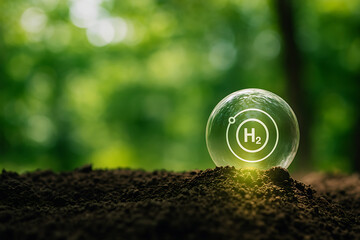 Clean hydrogen energy for a sustainable future. A glass globe with the H2 symbol on the ground and a natural green background.