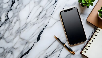 Overhead shot of a smartphone, pen, notebook, and small potted plant on a marble surface.