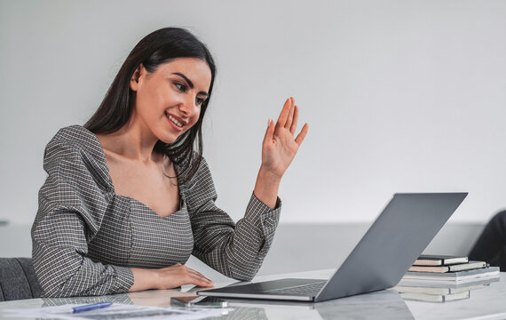 Woman communicating via laptop, modern realistic style, neutral office background, concept of video conferencing and remote business interaction