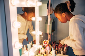 Girl organizing make-up products at illuminated dressing table in home