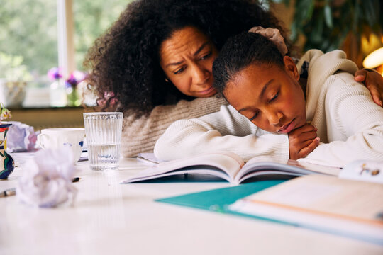 Mother embracing sad daughter studying at home