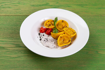 Ravioli on a plate. On a green background.