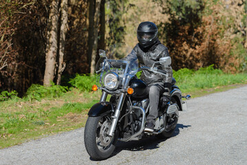 Naklejka premium biker on a custom classic motorcycle rides down the road, road traffic