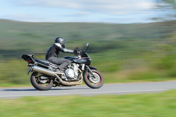 biker on a sport motorcycle rides fast while leaning on a turn on a winding road, motion blur highlighting the dynamic action © sergiy1975