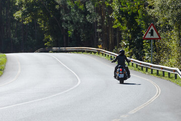 biker on a custom classic motorcycle rides down the road, road traffic