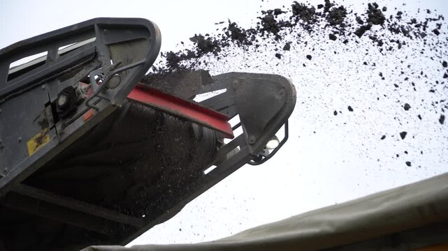 Special machine pours small black gravel into a truck. Road milling machine removes old asphalt. 
Repair work on the road. Workers remove the old asphalt and laid a new one. 