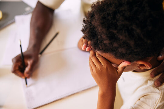 High angle view of boy stressed boy studying with father