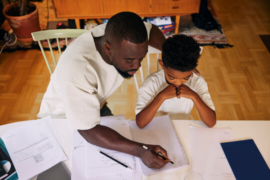 High angle view of father teaching son while solving math problem at home