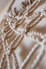 Close-up of a handmade macrame wall hanging. The intricate knots and patterns are visible, showcasing the craftsmanship and texture of the natural fibers.