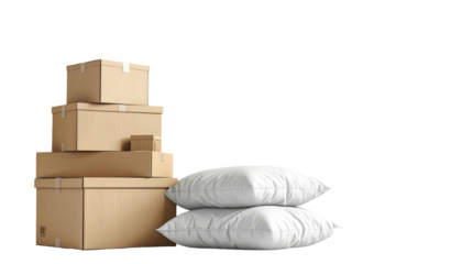 Stack of taped cardboard boxes beside two fluffy white pillows against black