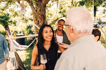Happy woman holding wineglass greeting senior man at social gathering party