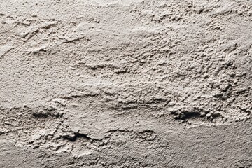 Fototapeta premium Concrete wall with uneven texture and shadows in bright, natural light. Ideal for backgrounds that need a rough, organic, or urban design feel.