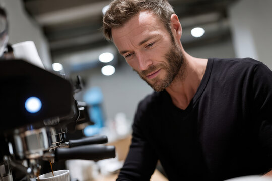 This image captures a skilled barista meticulously preparing coffee, showcasing his dedication to craft and the love for creating the perfect brew in a modern café environment.