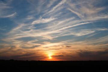 Obraz premium The sun rises over the horizon, painting beautiful clouds.