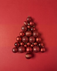festive christmas tree made of red ornaments on a red background, flat lay.