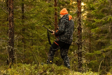Hunter with his hunting rifle outdoor in the autumn wilderness hunting moose