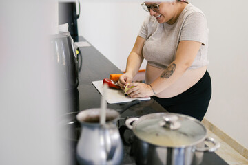 Pregnant colombian woman preparing vegetables in a modern kitchen