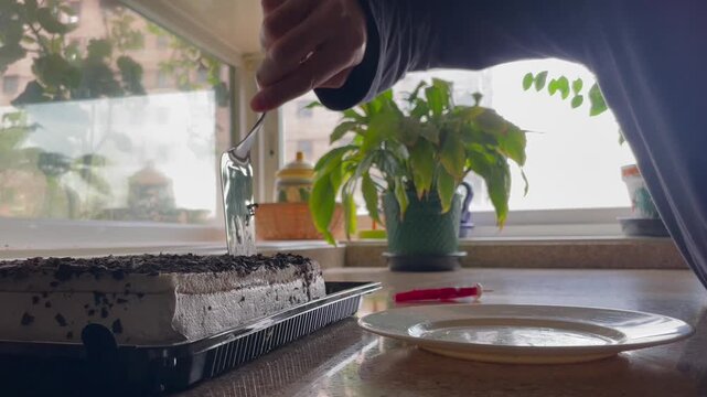 Preparando, cortando y emplatando un trozo de tarta de cumplea&ntilde;os con esp&aacute;tula servido en plato en la encimera de la cocina