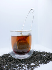 Glass Cup of Black Tea with Infuser and Loose Leaves on White Background