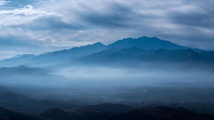 Fototapeta premium A vast mountain range shrouded in mist and fog under a dramatic cloudy sky