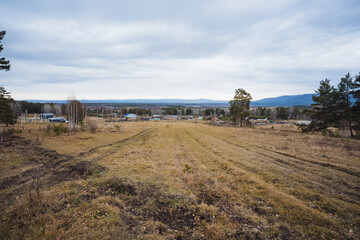 Peaceful agricultural landscape with cloudy skies, Calm rural plains with soft hills and overcast sky, Relaxed agricultural region surrounded by rolling hills under cloudy and overcast sky