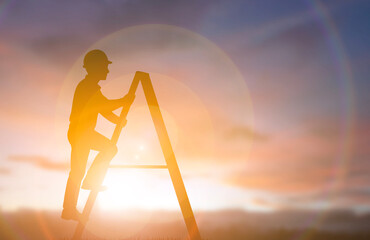 Silhouette engineer climbing A-frame ladder against sunset sky