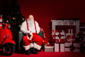 Santa Claus rests by a Christmas tree with gifts and a red background in a festive workshop scene...