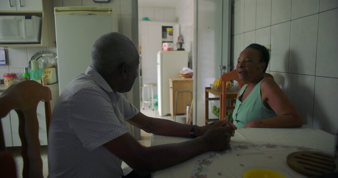 Elderly couple of African descent sharing a thoughtful moment at a dining table, showcasing connection, family bonds, and the simplicity of everyday life in a home setting