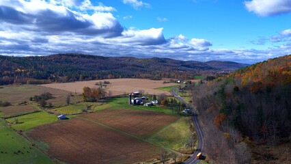Pennsylvania countryside with rural farmland, green fields and mountains under sunny sky with clouds during Autumn  Fall season colors