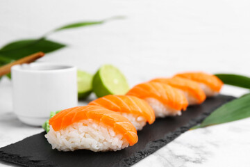 Delicious nigiri sushi with salmon on white marble table, closeup