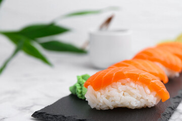 Delicious nigiri sushi with salmon and wasabi on white marble table, closeup. Space for text