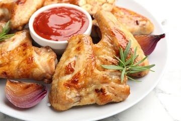 Delicious grilled chicken wings served on white marble table, closeup