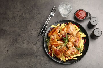 Delicious grilled chicken wings with french fries served on grey table, flat lay. Space for text
