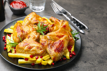 Delicious grilled chicken wings with french fries served on grey table, closeup