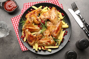 Delicious grilled chicken wings with french fries served on grey table, flat lay