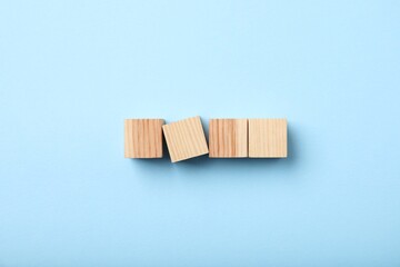 Wooden cubes on light blue background, top view